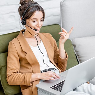 Special courses Goethe-Institut Eine lächelnde junge Frau mit Headset lernt am Laptop.