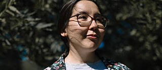Eine dunkelhaarige Frau an einem sonnigen Tag. 