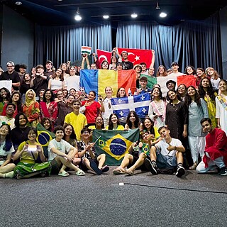 Os alunos/-as ficam em um palco e exibem bandeiras nacionais