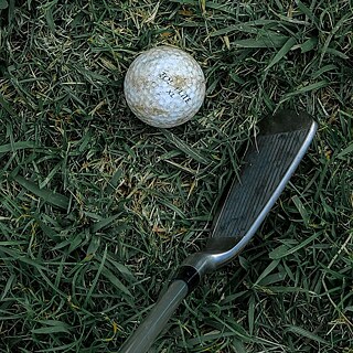 Golfschläger und -ball im Gras