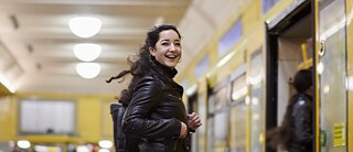 Eine Frau schaut lachend in die Kamera, bevor sie in die U-Bahn steigt.
